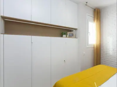 a bedroom with white cabinets and a yellow bed at Sunny Playa Apartment in Barcelona