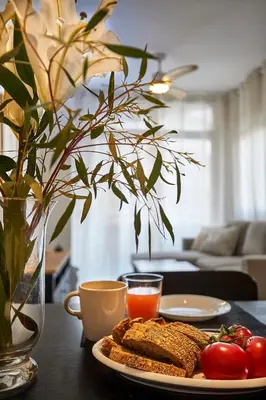 a plate of toast and tomatoes on a table with a vase at BBarcelona Modern Eixample Flat in Barcelona