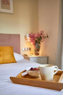 a tray with a cup and a bowl of cherries on a bed at BBarcelona Modern Eixample Flat in Barcelona