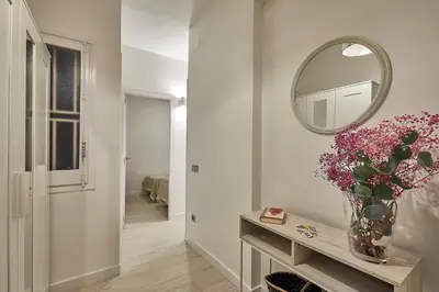 a hallway with a vase of flowers on a table with a mirror at BBarcelona Modern Eixample Flat in Barcelona