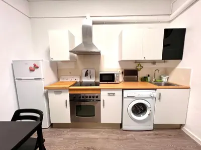 a kitchen with white cabinets and a washer and dryer at Poble Sec. Excelente ubicación cerca de la playa y de las Ramblas in Barcelona