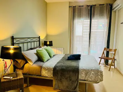 a bedroom with a bed with green pillows and a window at Magic Camp Nou in Barcelona