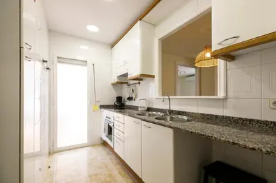 a kitchen with white cabinets and a sink and a window at Be Barcelona Eixample Urquinaona II in Barcelona