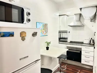 a kitchen with a white refrigerator and a table at Nice apartment close PARK GÜELL 2 in Barcelona