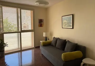 a living room with a couch and two windows at Luminoso apartamento en Canet de Mar cercano a la playa y a Barcelona in Canet de Mar