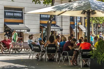 a group of people sitting at tables under an umbrella at Habitat Apartments Pedrera in Barcelona