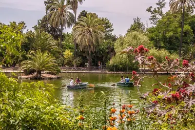 people in boats on a pond in a park with palm trees at Habitat Apartments Born in Barcelona