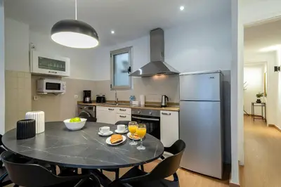 a kitchen with a table with chairs and a refrigerator at Habitat Apartments Art in Barcelona