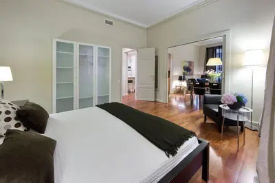 a bedroom with a white bed and a living room at Habitat Apartments Art in Barcelona