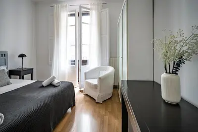 a bedroom with a bed and a white chair at Habitat Apartments Art in Barcelona