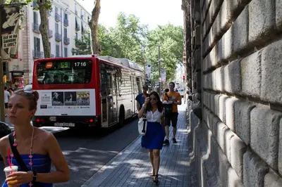 a woman walking down a street in front of a bus at Habitat apartments Barcelona Center in Barcelona
