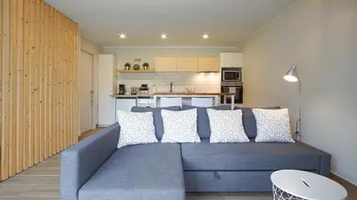 a living room with a blue couch and a kitchen at Holidays en Arenys de Mar y Montaña in Arenys de Mar