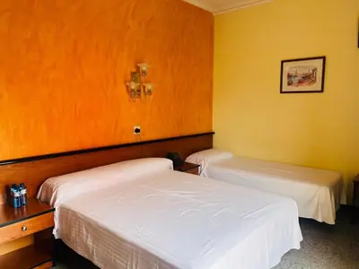 two beds in a room with yellow walls at HOTEL CONTINENTAL in Calella