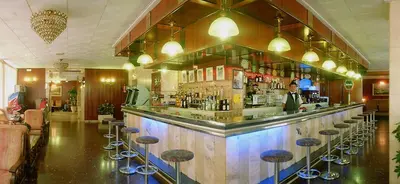a bar with stools and a man standing behind it at HOTEL CONTINENTAL in Calella