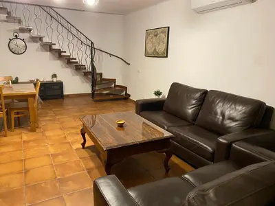 a living room with a leather couch and a table at Masia Can Llonch in Palau-Solità i Plegamans