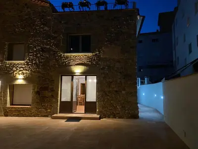 a stone building with a door at night at Masia Can Llonch in Palau-Solità i Plegamans