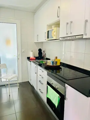 a kitchen with white cabinets and a black counter top at Attic360Views in Barcelona