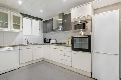 a white kitchen with white cabinets and appliances at The Collection Barcelona - Elegant 3-bedroom Apartment in the Heart of BCN in Barcelona