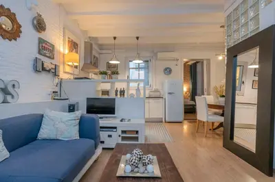 a living room with a blue couch and a kitchen at The Collection Barcelona - Exclusive 2 bedroom apartment in the city center in Barcelona