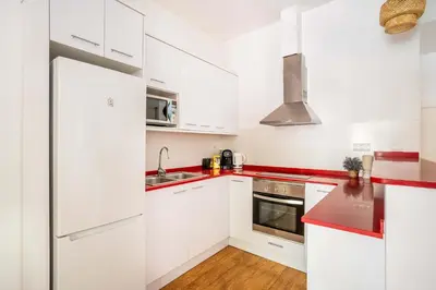 a kitchen with white cabinets and red counter tops at The Collection Barcelona - Pl Universitat Bright and cozy 2BD - 2BTH in Barcelona