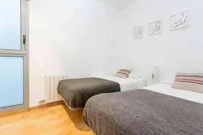 two beds in a white room with a window at The Collection Barcelona - Spacious and Elegant 4 Bedroom with Private Terrace in Barcelona