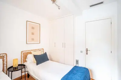 a white bedroom with a bed and a table at The Collection Barcelona - Pl Universitat Comfortable 3BD with private patio in Barcelona