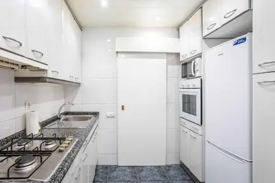 a white kitchen with a sink and a stove at The Collection Barcelona - Next to Sagrada Familia 4-bedroom Apartment in Barcelona