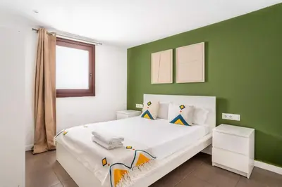 a bedroom with a white bed with green walls at The Collection Barcelona - Modern and bright 4BD triplex in Paralel! in Barcelona