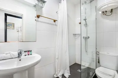 a white bathroom with a shower and a sink at The Collection Barcelona - 4- Bedroom Apartment in Gracia Village in Barcelona