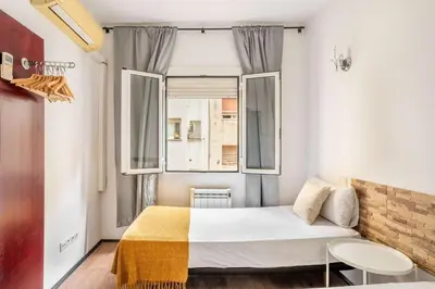 a small bedroom with a bed and a window at The Collection Barcelona - 4- Bedroom Apartment in Gracia Village in Barcelona