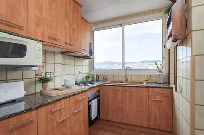 a kitchen with wooden cabinets and a large window at The Collection Barcelona - City View Penthouse - 2 Bedroom Suite in Barcelona