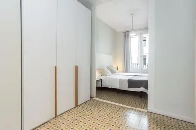 a white bedroom with a large white bed and a lamp at The Collection Barcelona - 4bedroom apartment with a balcony in Las Ramblas 1 2 in Barcelona