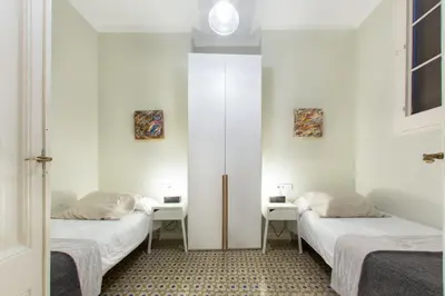 two beds in a room with two tables and a mirror at The Collection Barcelona - 4bedroom apart with balcony in Las Ramblas 3-2 in Barcelona