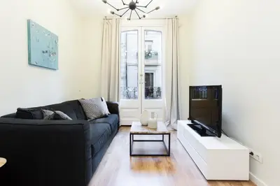 a living room with a black couch and a tv at The Collection Barcelona - Bright and modern 2bedroom in Las Ramblas 2 1A in Barcelona