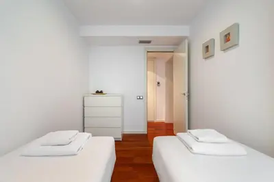 two beds in a room with white walls and wooden floors at The Collection Barcelona - Plaça Catalunya Modern 2bedroom with balcony in Barcelona