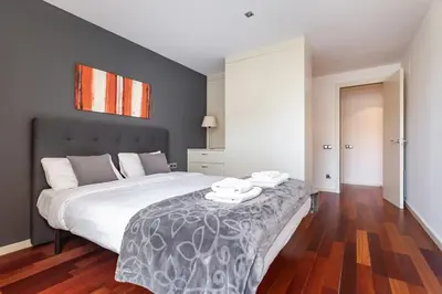 a bedroom with a large bed and a black chair at The Collection Barcelona - 3bedroom Duplex with balcony in plaza Cataluña in Barcelona