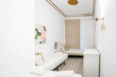 a white bedroom with a bed and a chair at The Collection Barcelona - Placa Catalunya V Charming and Exquisite 5Bd Apartment with Large Balcony in Barcelona