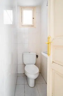 a white bathroom with a toilet and a window at The Collection Barcelona - Huge historic 5BD with private Terrace! in Barcelona