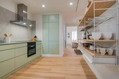 a kitchen with green cabinets and wooden floors at The Collection Barcelona - Amazing 5 bd 5 bathroom next to Plaza Catalunya in Barcelona