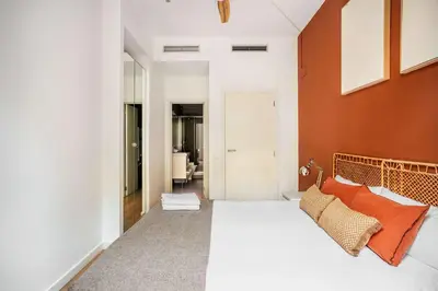 a bedroom with a white bed with orange pillows at The Collection Barcelona - Perfectly located 4bed 4bath apartment in Eixample in Barcelona