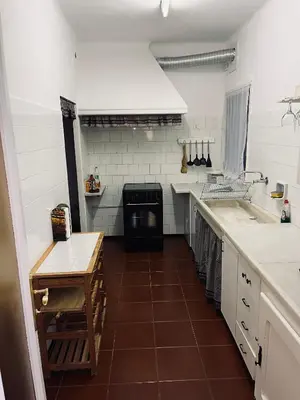 a kitchen with white walls and a brown tile floor at Casa iaia in Monistrol