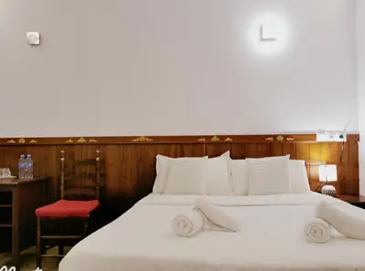 a bedroom with a large white bed with a red chair at Barcelona CoronaHostal in Badalona