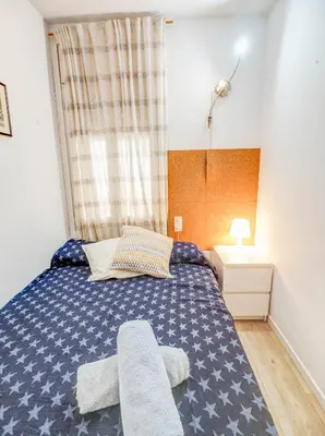 a bedroom with a blue bed and a window at Clarimar Beach Apartment by Hello Homes Sitges in Sitges