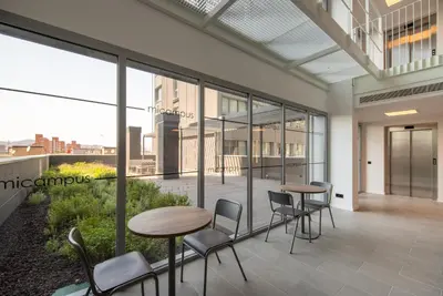 a balcony with tables and chairs in a building at Micampus Barcelona Student Residence in Barcelona