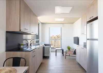 a kitchen with wooden cabinets and a living room at Micampus Barcelona Student Residence in Barcelona