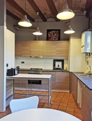 a kitchen with wooden cabinets and a table with chairs at Habitació polivalent al centre de Manresa in Manresa