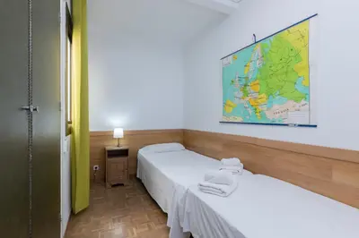 two beds in a room with a map on the wall at ApartEasy - Atic Sants in Barcelona