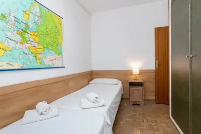 two beds in a room with a map on the wall at ApartEasy - Atic Sants in Barcelona