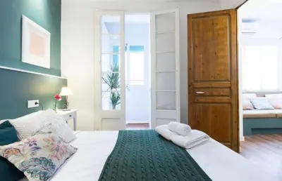 a bedroom with a bed with white sheets and a green blanket at LEPANTO APARTMENTS 150m FROM SAGRADA FAMILIA in Barcelona
