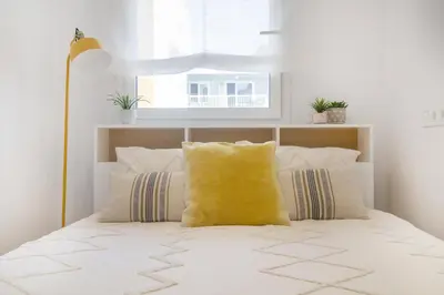 a bedroom with a bed with a yellow pillow at Vivalidays Apartour - Calella in Calella